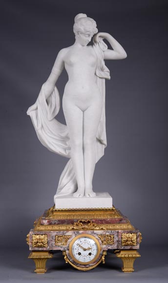 Peach blossom marble and gilt bronze clock surmounted by a statuary white marble   sculpture representing Phryne in front of his judges signed  Peach blossom marble and gilt bronze clock surmounted by a statuary white marble   sculpture representing Phryne in front of his judges signed