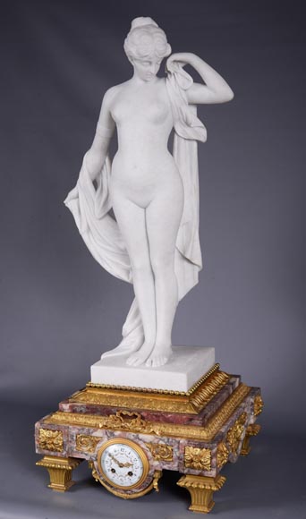 Peach blossom marble and gilt bronze clock surmounted by a statuary white marble   sculpture representing Phryne in front of his judges signed  Peach blossom marble and gilt bronze clock surmounted by a statuary white marble   sculpture representing Phryne in front of his judges signed