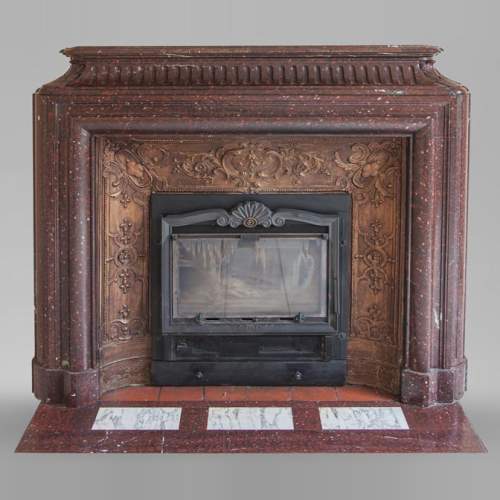 An antique Louis XIV style fireplace, with acroterion and Bollection, made out of Rouge Griotte marble