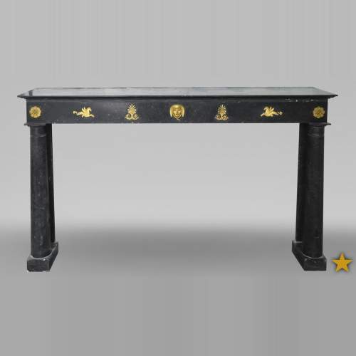 An antique Empire fireplace made out of black marble, witrh bronze ornaments and detached columns