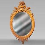 Louis XVI oval mirror in gilt wood with a vase and flowers