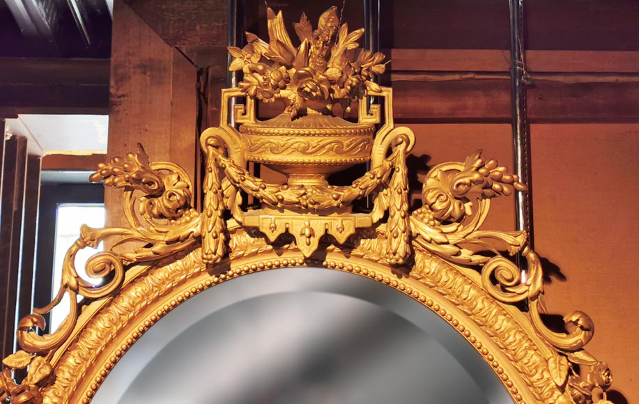 Louis XVI oval mirror in gilt wood with a vase and flowers