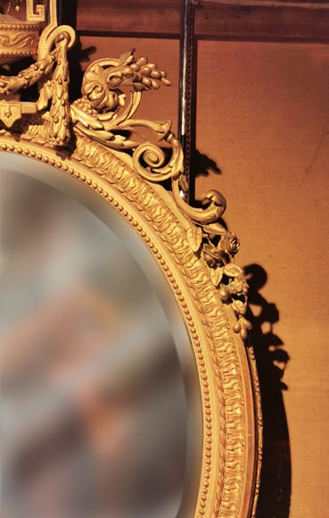 Louis XVI oval mirror in gilt wood with a vase and flowers
