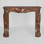 An antique Louis XV style fireplace, Pompadour model, made out of Rouge du Nord marble