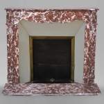An antique Louis XV style fireplace, Pompadour model, made out of Rouge du Nord marble