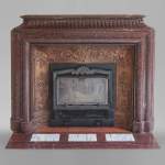 An antique Louis XIV style fireplace, with acroterion and Bollection, made out of Rouge Griotte marble