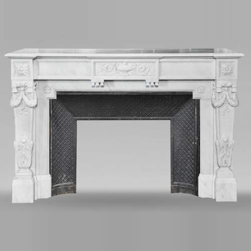 A Louis XVI style fireplace, richly decorated with garlands and vases, in Carrara marble